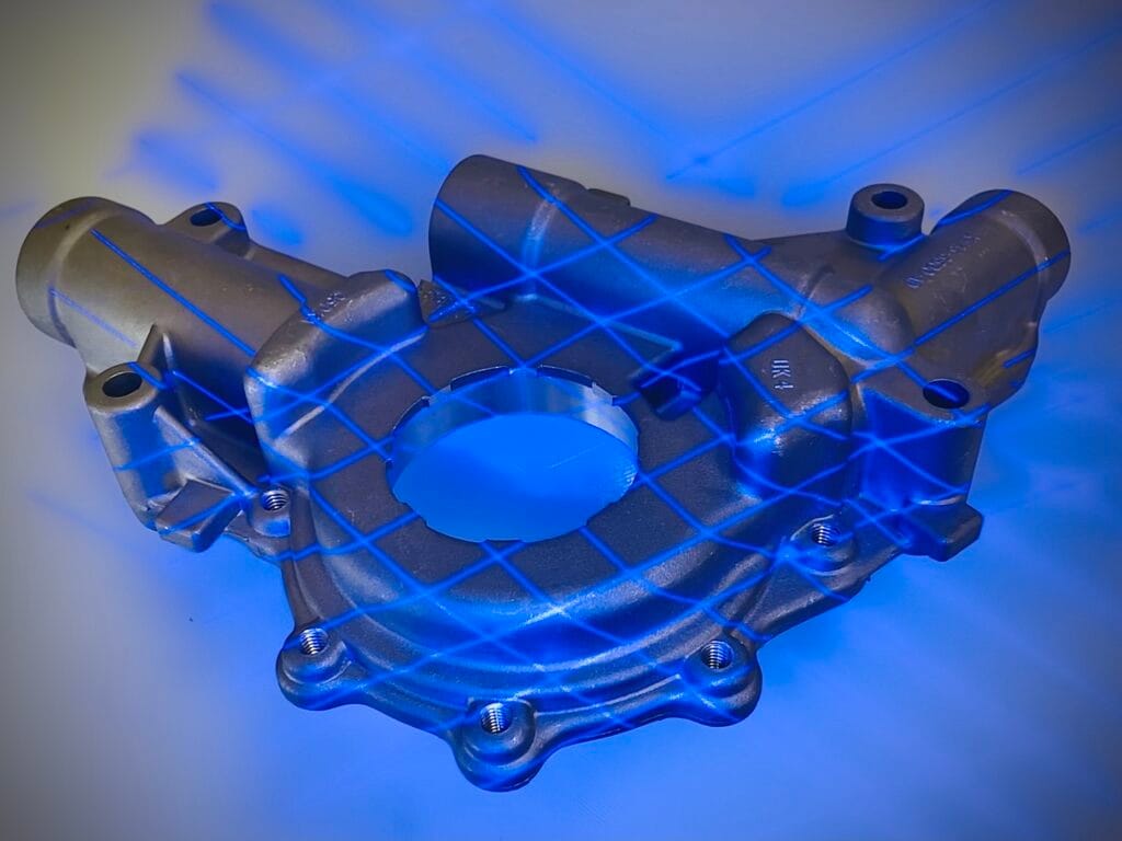 Silver automotive part with crossing blue laser lines over it during 3D scanning