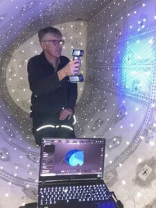 Adrian scanning inside Vulcan XL426 fuel tank, blue scanner light on surface, laptop shows model.