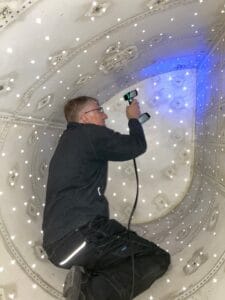 Scanning inside Vulcan bomber fuel tank. Blue light from scanner shines onto scan surface.