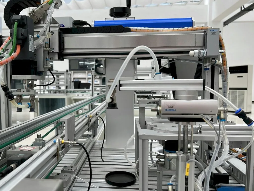 Silver production line with tools and sensors operating on parts moving along conveyor belt.