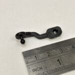 Photo of a small black link arm from Ford Focus AC next to a ruler to indicate size